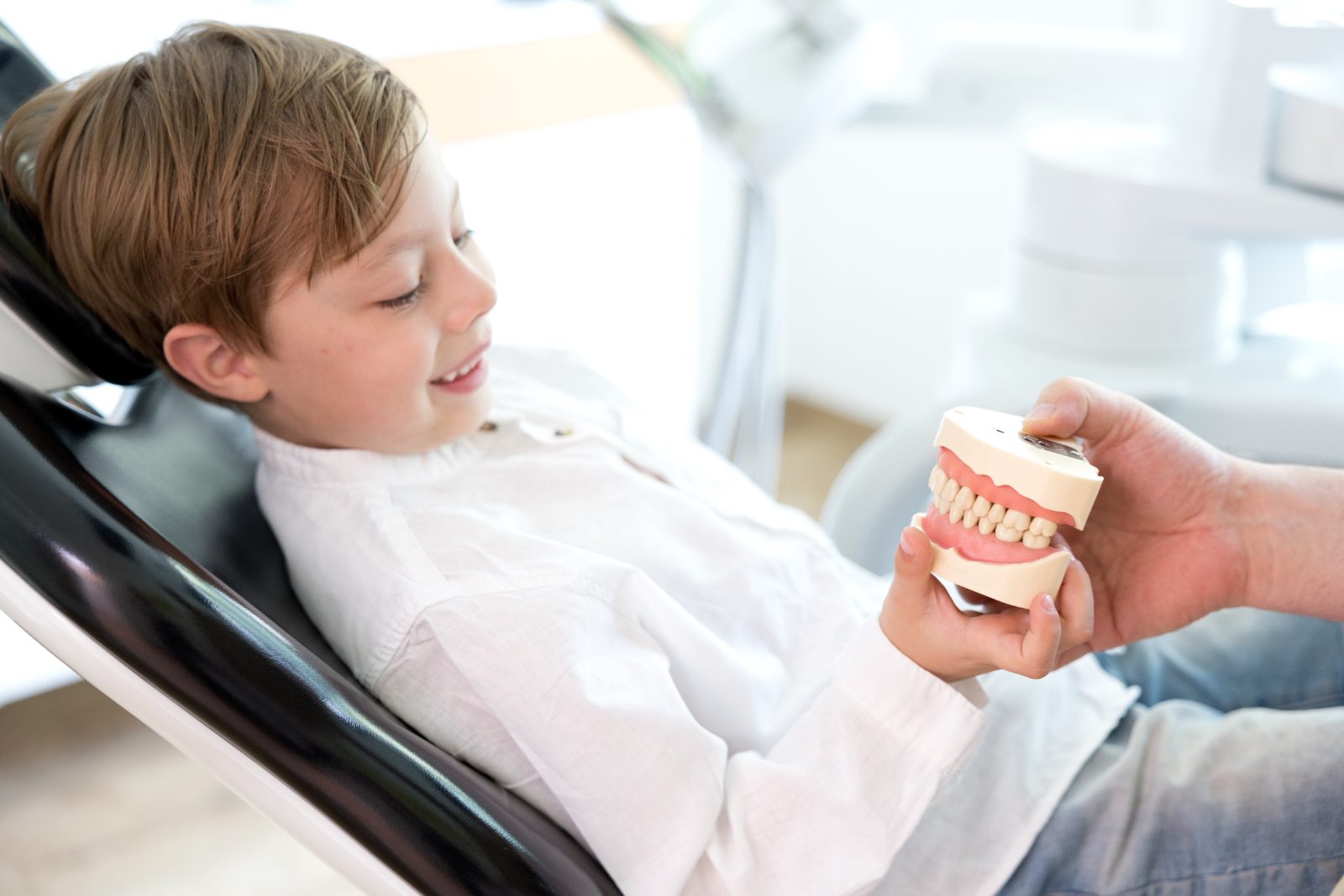 Kind erkundet ein Zahnmodell im Behandlungszimmer